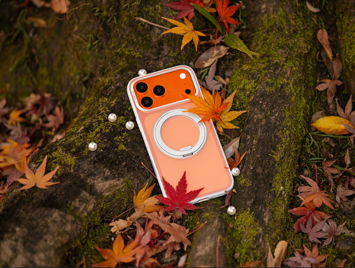 TORRAS orange iPhone case with MagSafe stand surrounded by autumn leaves
