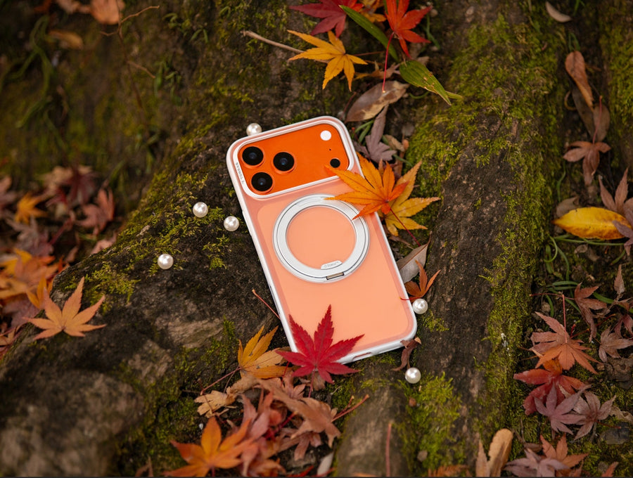 TORRAS orange iPhone case with MagSafe stand surrounded by autumn leaves