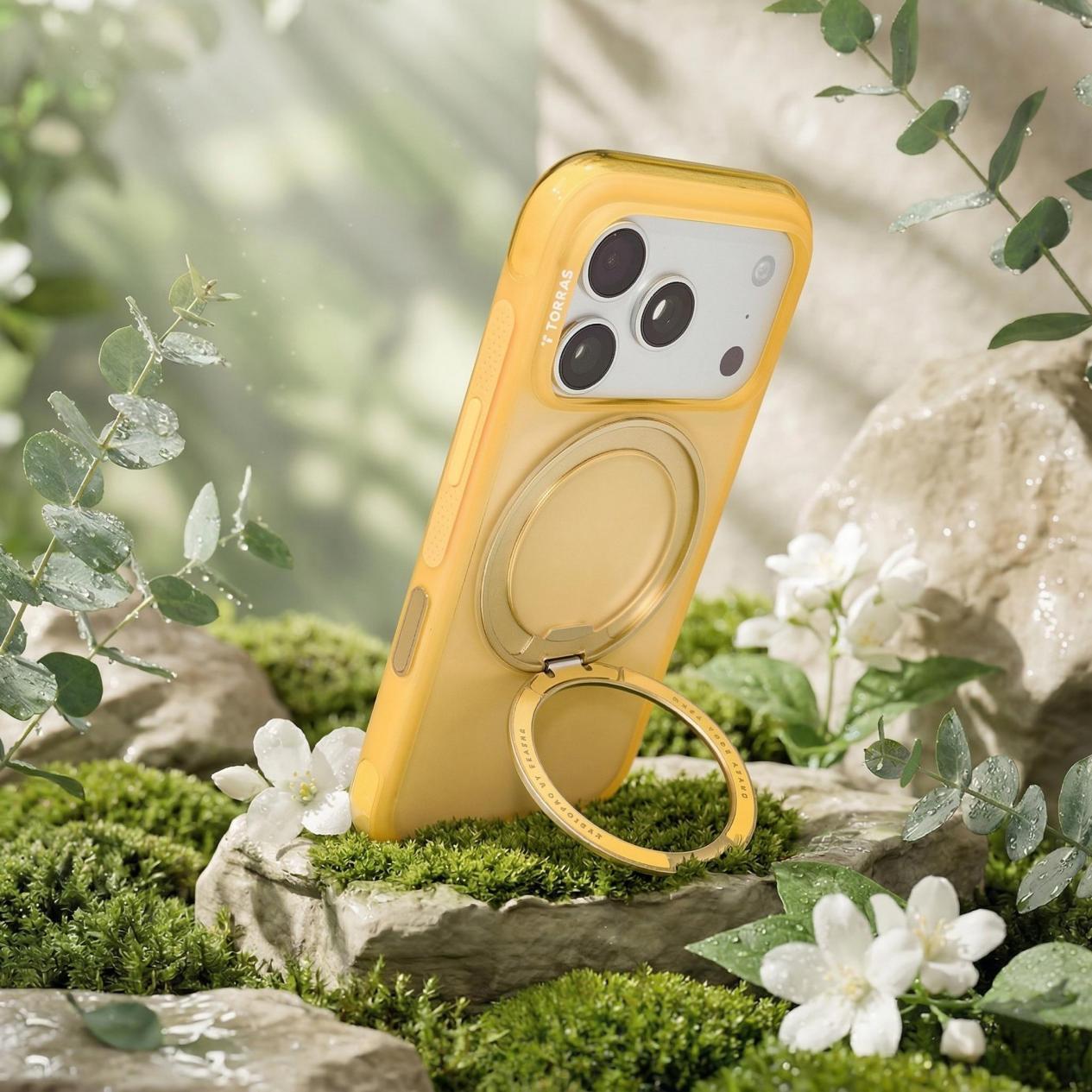 苔むした岩と花の上に置かれたTorras製iPhone 16イエローケース（スタンド付き）