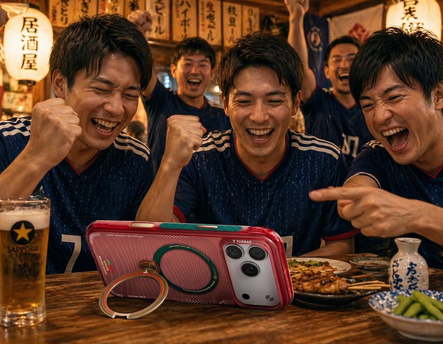 スポーツバーでTorrasのスマホリングスタンドを使い、2026年ワールドカップの試合をスマートフォンで観戦するユニフォーム姿の友人たち