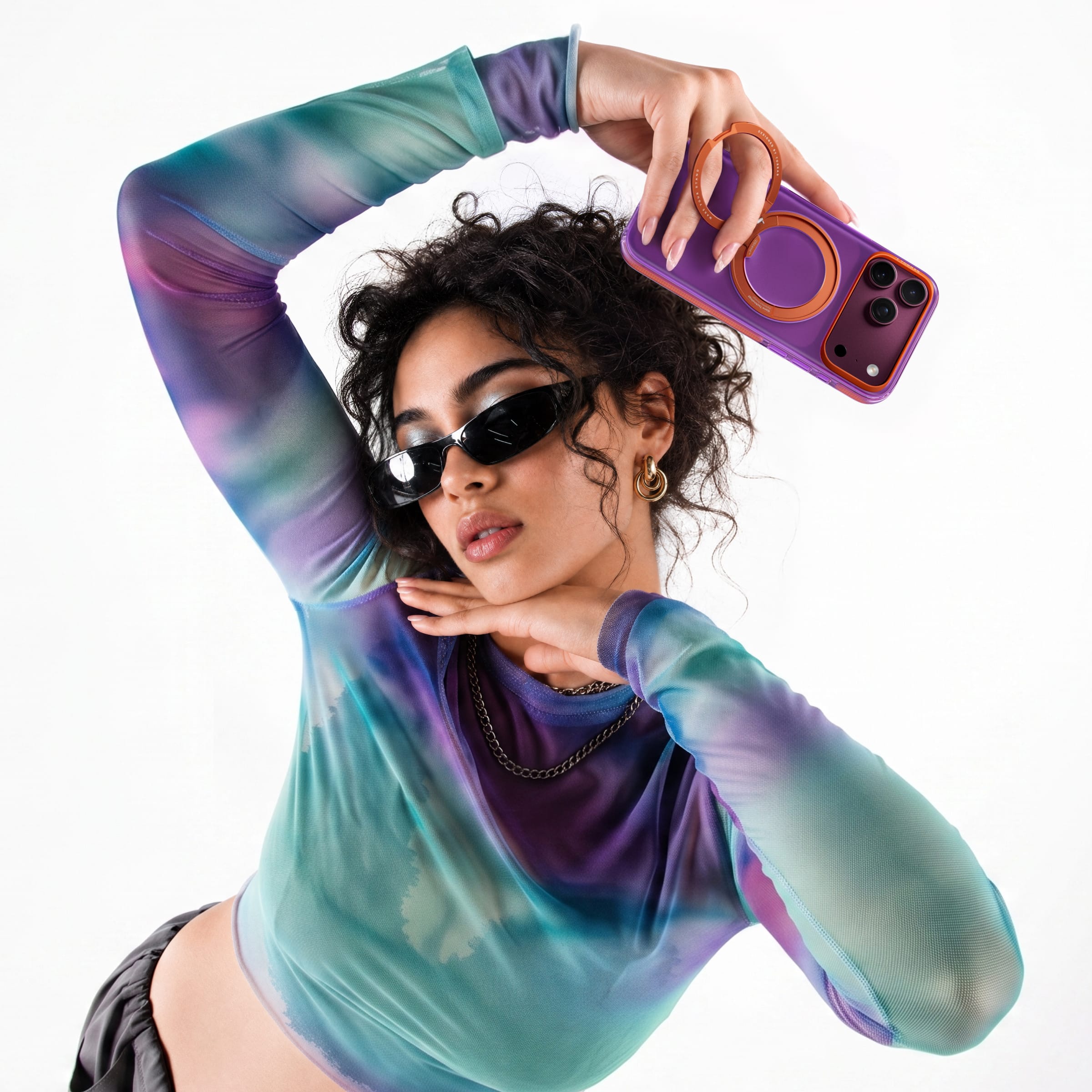 TORRAS Ostand O3 Hue ケース iPhone 18 Pro/Pro Max 対応、屋外で紫のクリアケースを手に持つ巻き髪の女性。