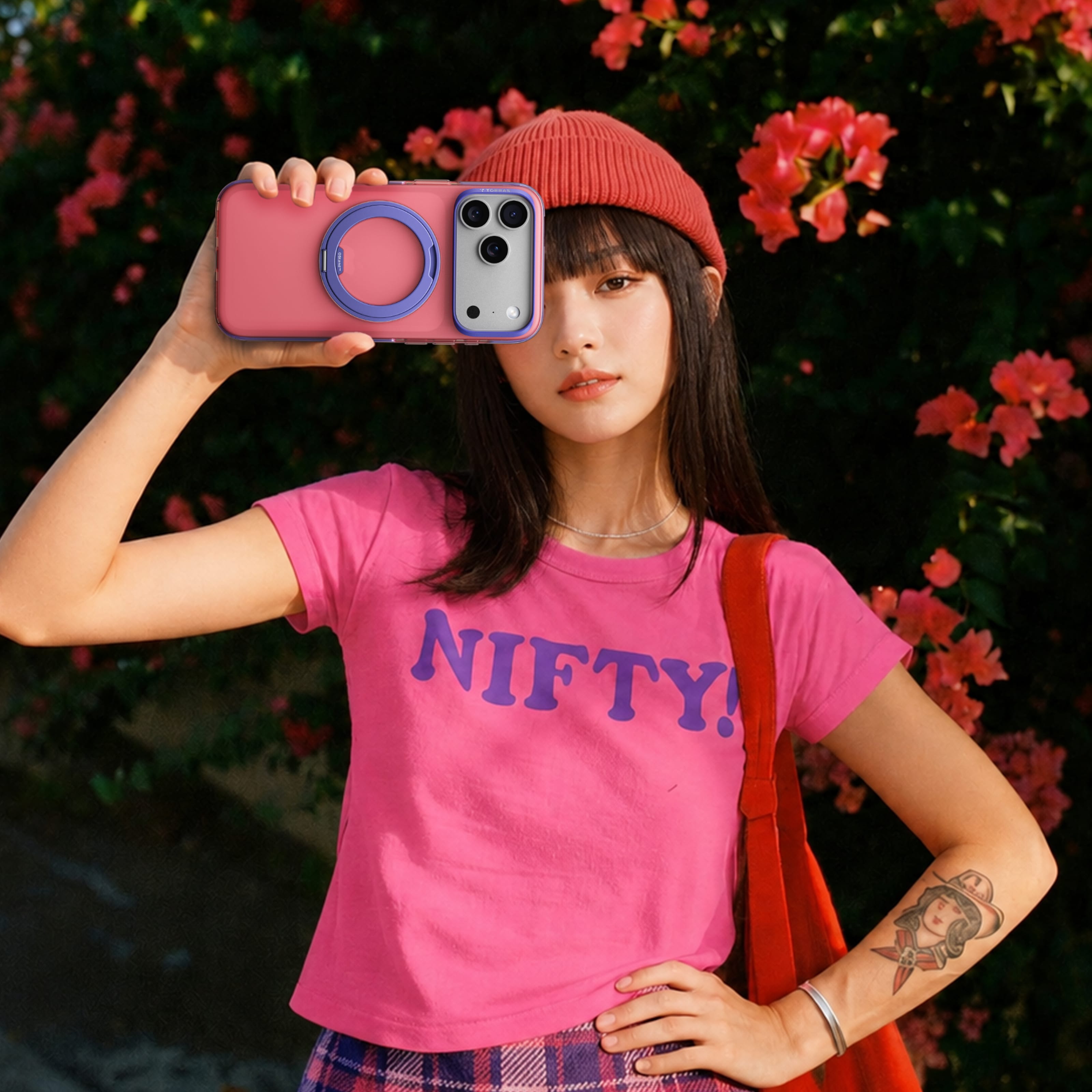 TORRAS Ostand O3 Hue ケース iPhone 18 Pro/Pro Max 対応、ピンクの「NIFTY」Tシャツの女性が屋外でピンクケースを手にするポートレート。