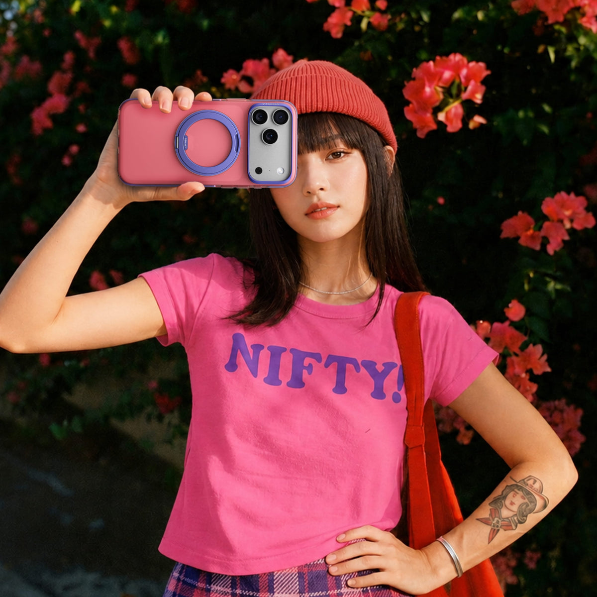 TORRAS Ostand O3 Hue ケース iPhone 18 Pro/Pro Max 対応、ピンクの「NIFTY」Tシャツの女性が屋外でピンクケースを手にするポートレート。