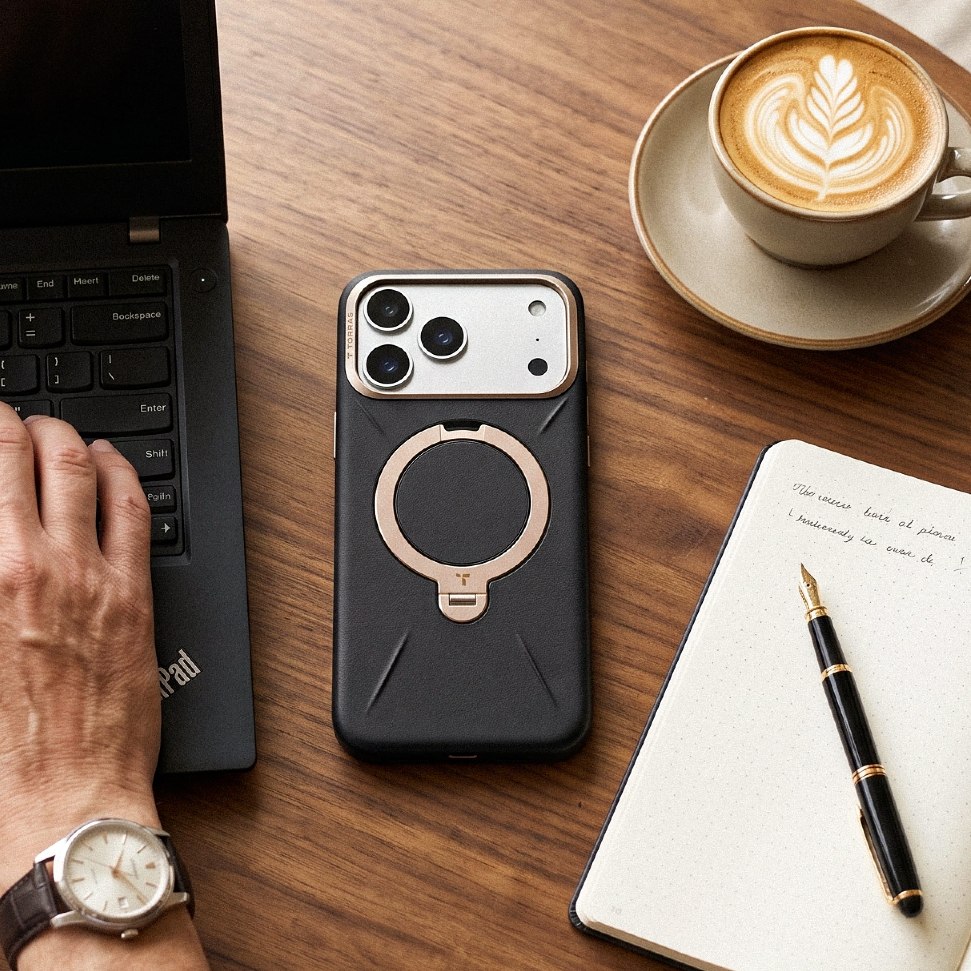 TORRAS Ostand Q3 レザートーン ケース iPhone 18 Pro/Pro Max 対応、ブラックの革調ケースとノートブック、ラテアートコーヒーの並ぶデスクシーン。